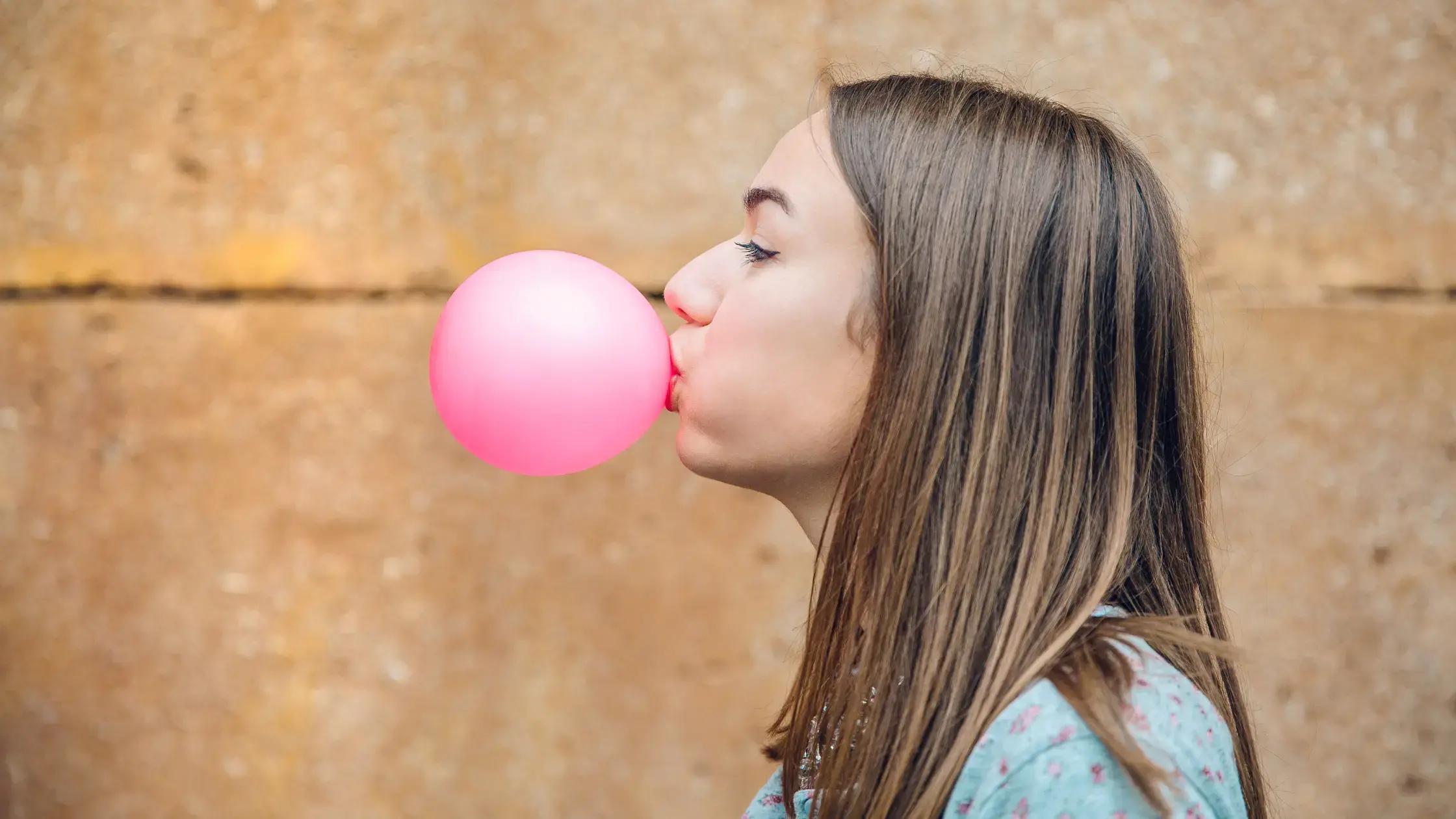 woman blowing a big bubble gum bubble about to pop